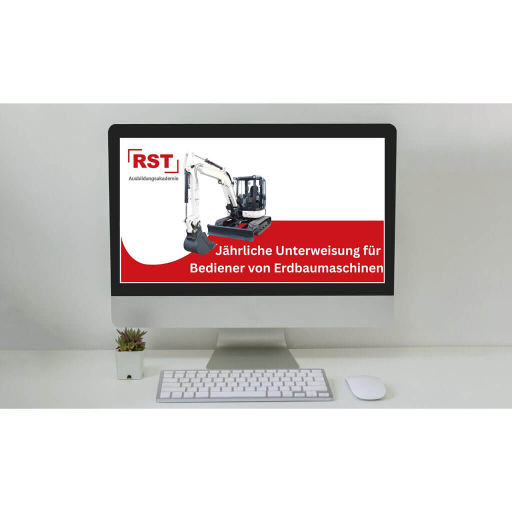 Monitor on a white desk displaying a red banner ad with an excavator graphic and the text 'RST Ausbildungsakademie' and 'Jährliche Unterweisung für Bediener von Erdbaumaschinen'; keyboard, mouse and a small plant visible on the desk.