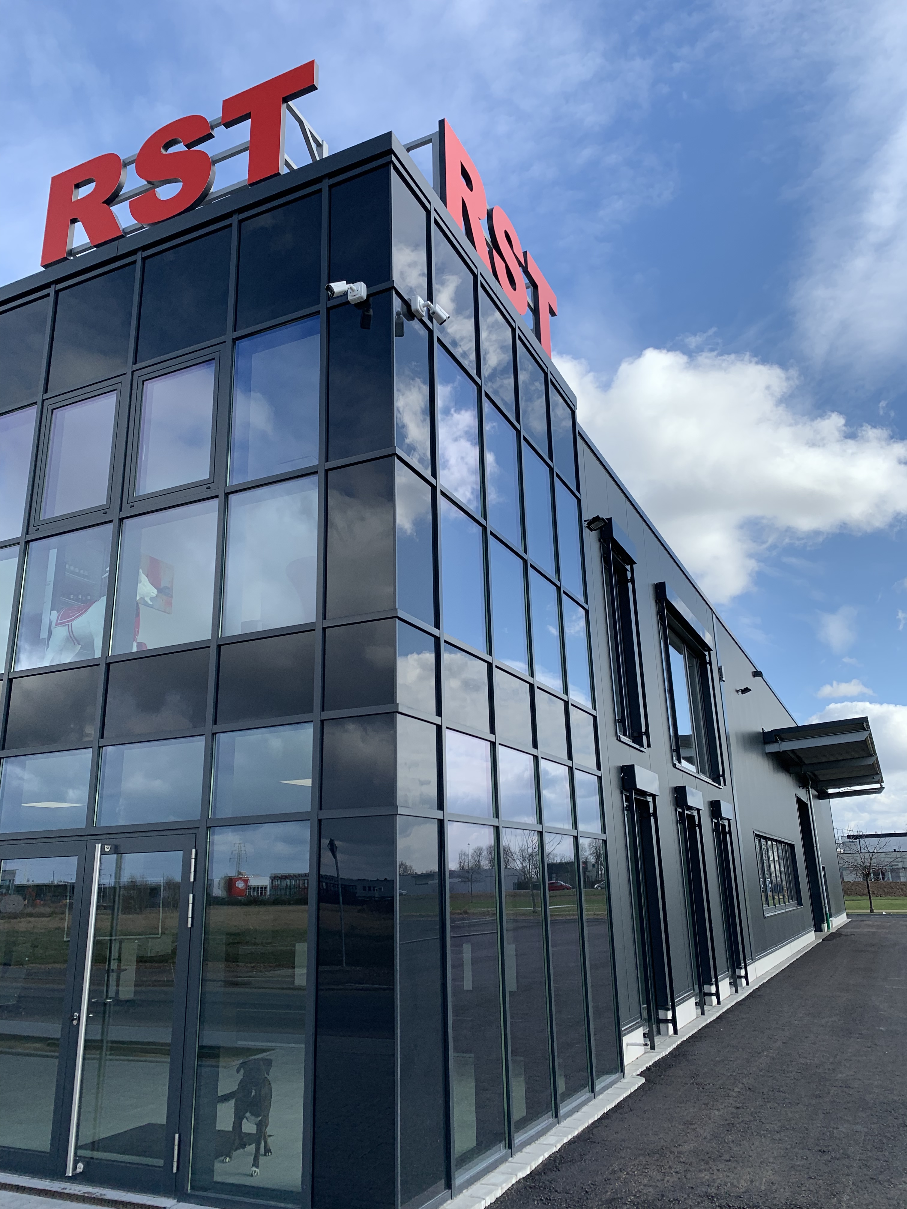 Left panel shows RST branding with photos of Ralf Schnirch and Melina Schnirch, contact details and a German slogan; right panel shows a modern RST office building with red logo on top.