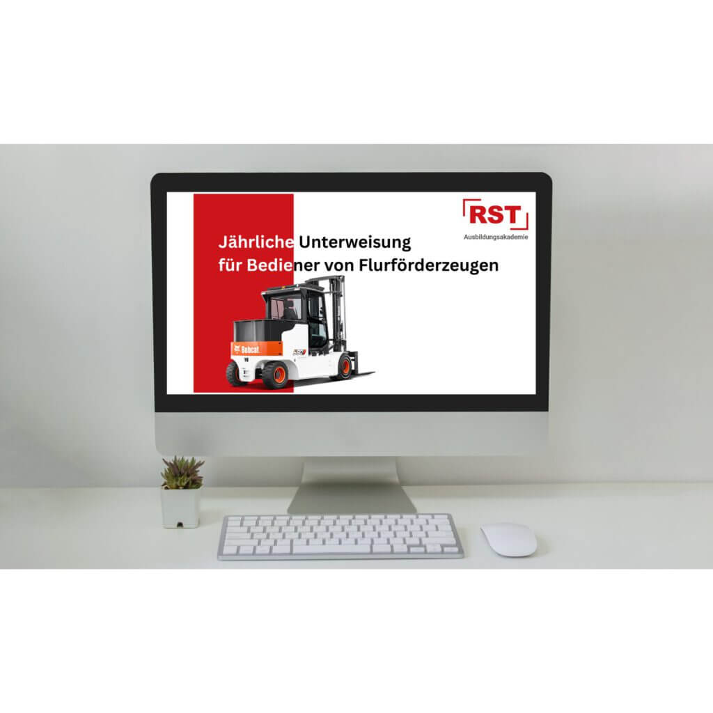 Desk setup with a monitor displaying a German forklift operator training poster (red/white design) on screen; keyboard and mouse in front, small plant on left.