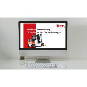 Desk setup with a monitor displaying a German forklift operator training poster (red/white design) on screen; keyboard and mouse in front, small plant on left.