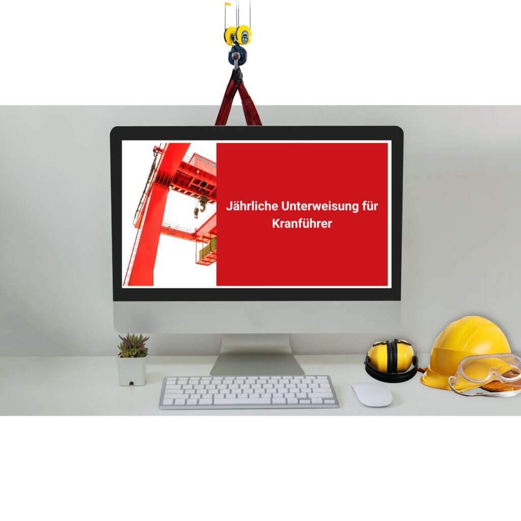 Computer monitor shows a red safety poster about annual crane operator training, with a red crane image on the left and German text on the right.