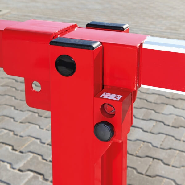 Nahaufnahme des Scharniers und des Verriegelungsmechanismus einer roten COMPACT Systemschranke mit Gegengewicht, die auf einer gepflasterten Fläche steht.