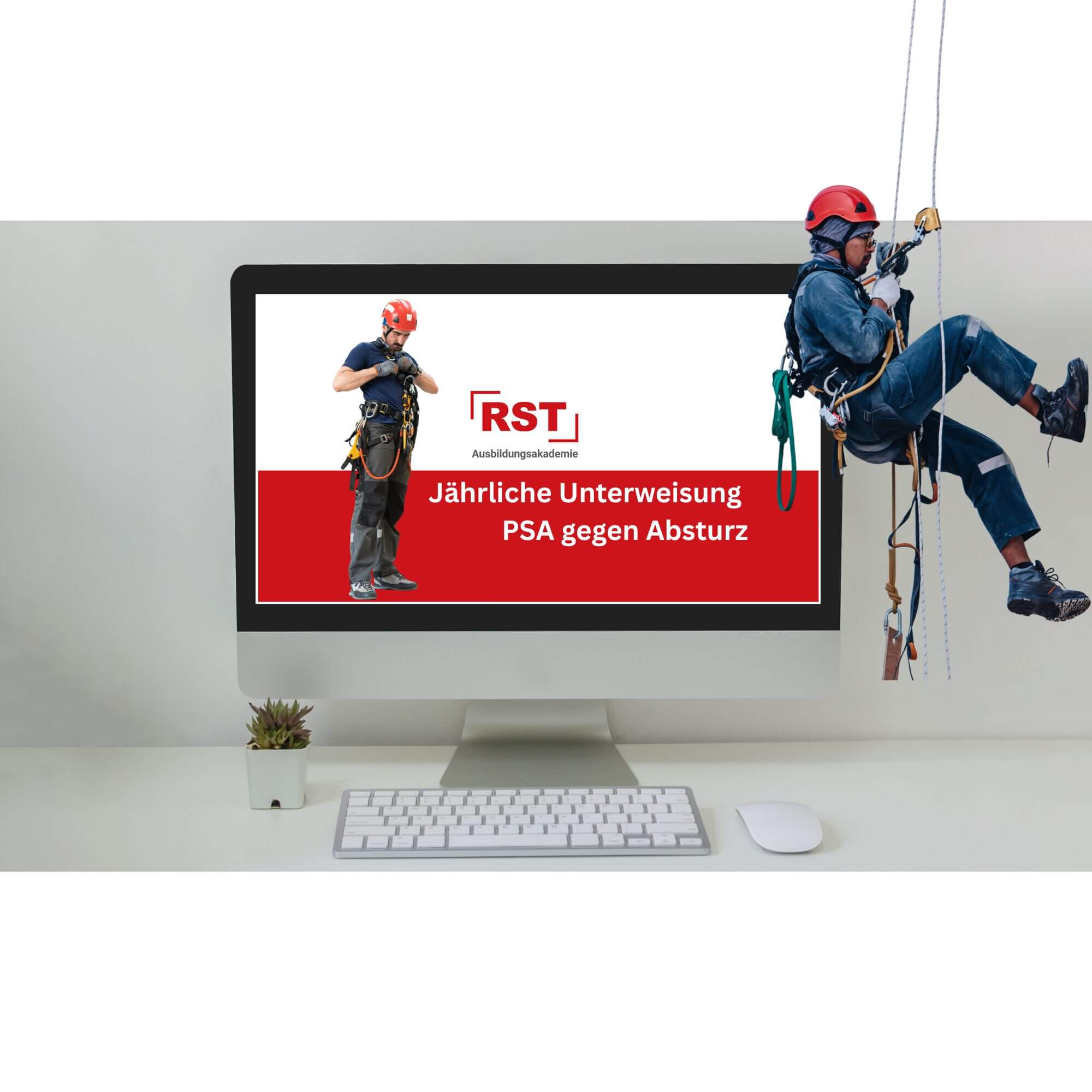 Desktop monitor displays a red-and-white advertisement for RST Ausbildungakademie with two workers in safety gear, set on a white desk with a keyboard, mouse, and a small succulent plant nearby.